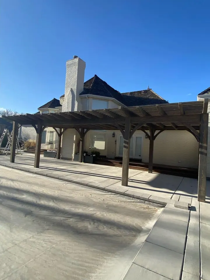 Two connected open-lattice pergolas over a driveway
