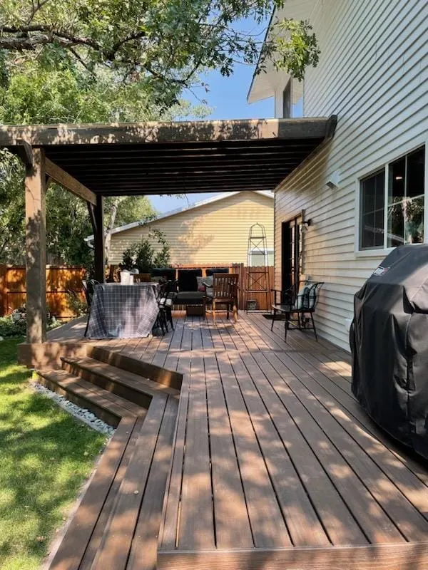 Covered deck with a hot tub and grill