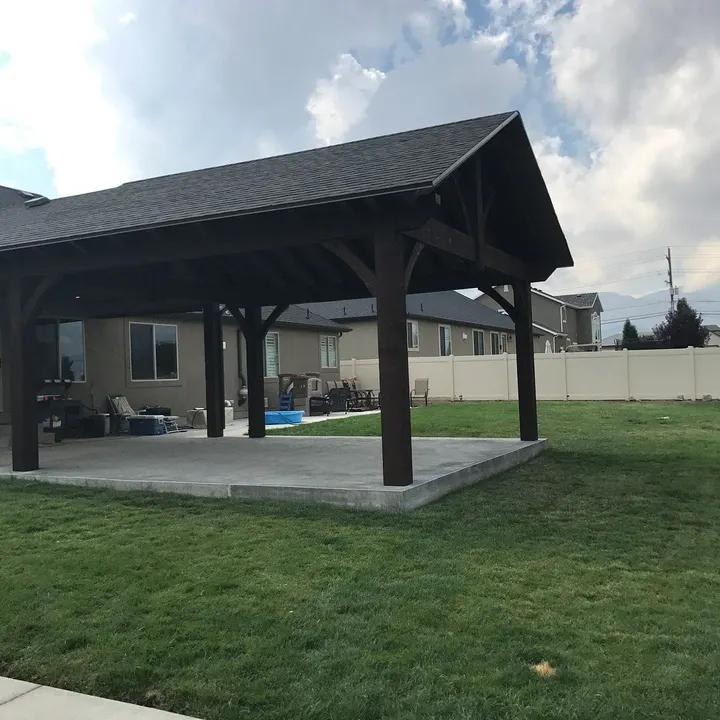 Dark-finished gabled pavilion on a backyard lawn