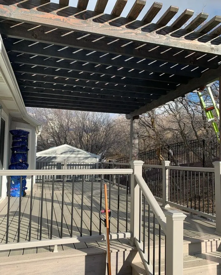 Dark pergola over a raised deck with white railing