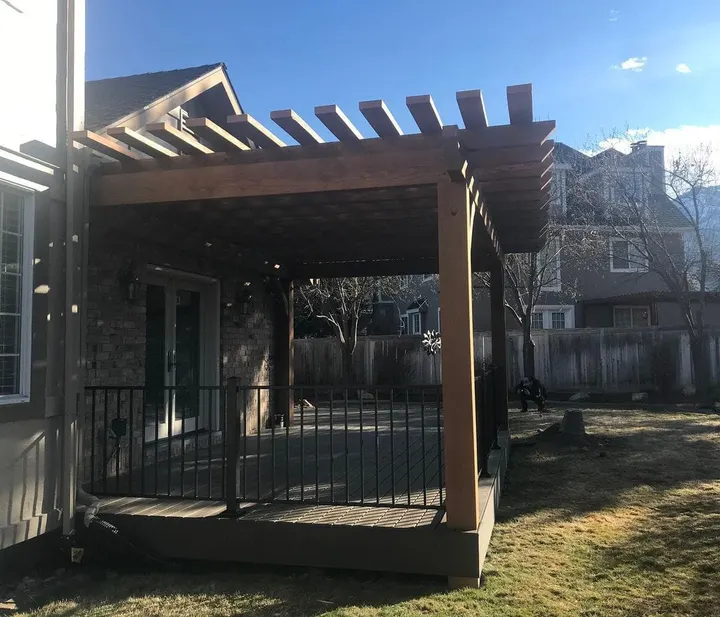 Dark open-lattice pergola over a small raised deck