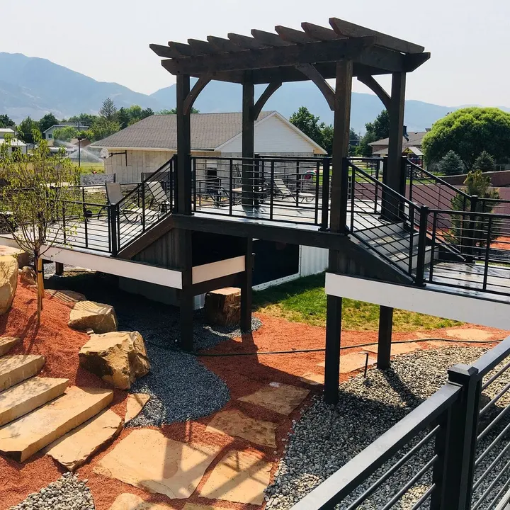 Elevated deck with black railing above landscaped ground