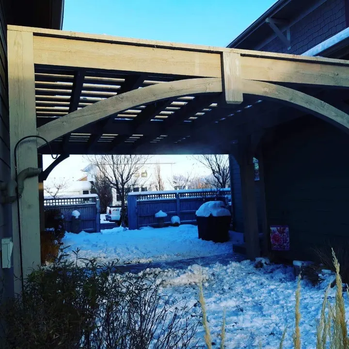 Covered patio with a hot tub in a snow-covered yard