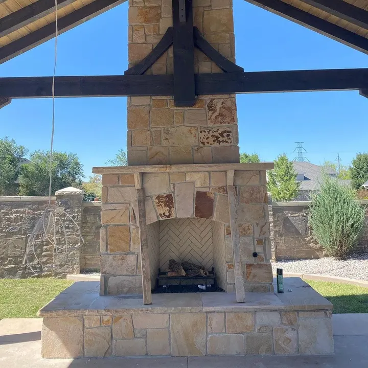 Stone outdoor fireplace beneath a timber pavilion