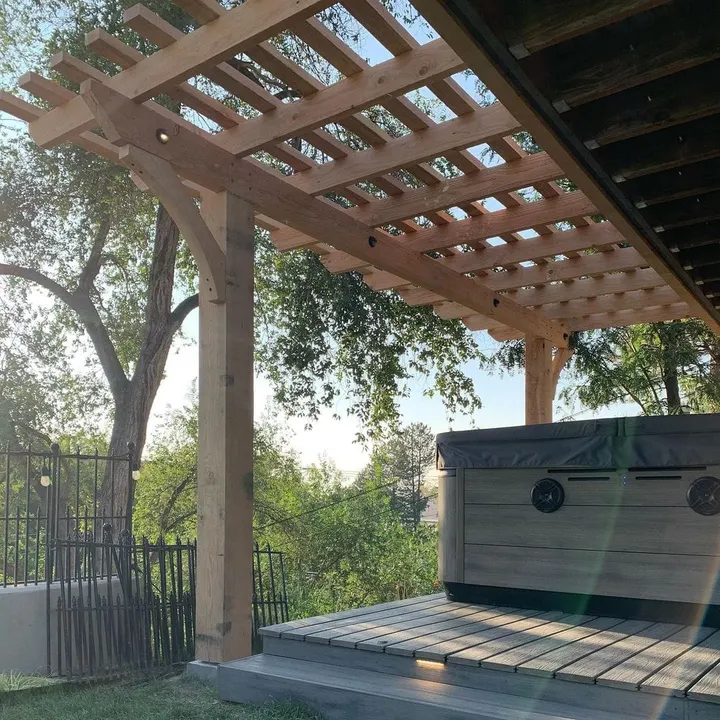 Open-lattice pergola over a hot tub beside mature trees