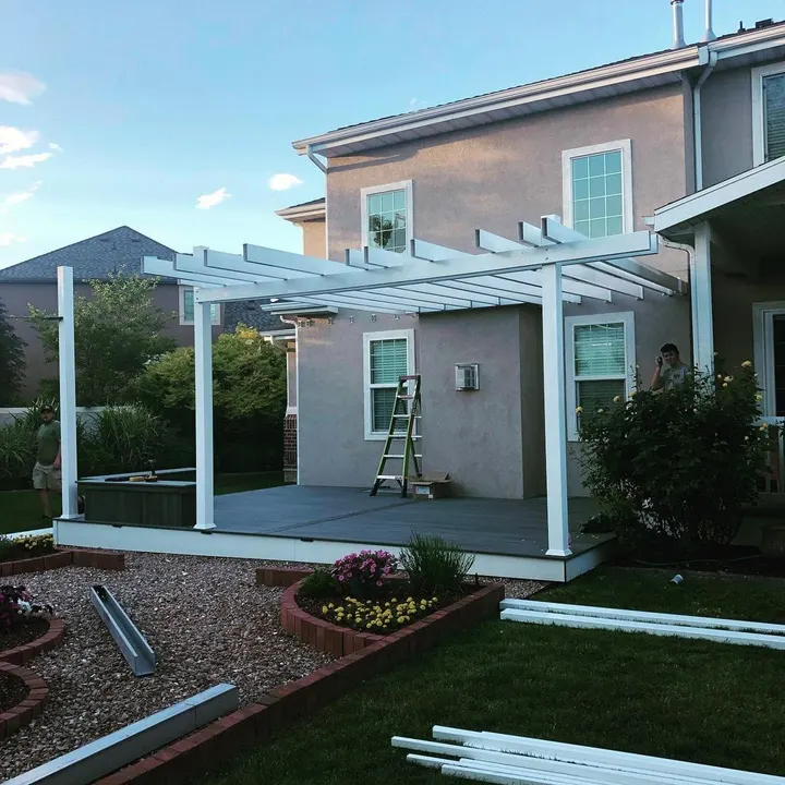 White pergola being installed over a backyard patio